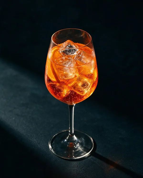 Orange Aperol Spritz i vinglas med is och apelsinskiva