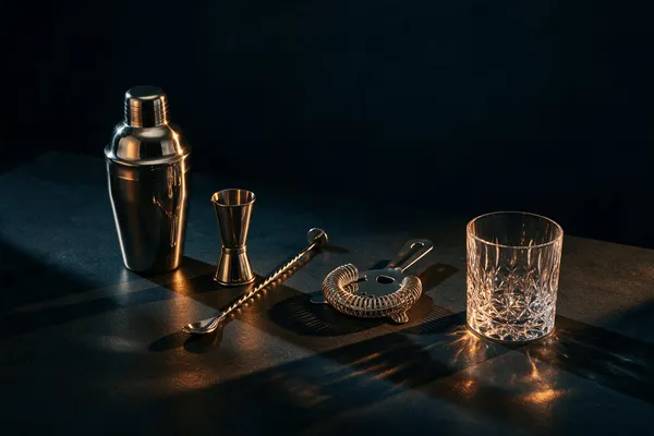 Shaker, måttglas, barsked och sil uppradade på ett bord