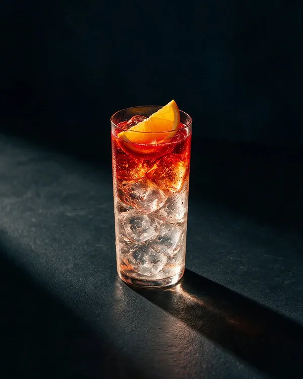 Klarröd Campari Soda i highballglas med is och en apelsinklyfta
