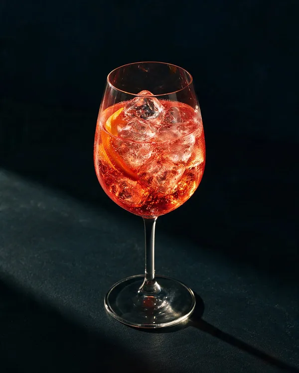 Rosa Sarti Spritz i stort vinglas med is, bubblor och en apelsinskiva